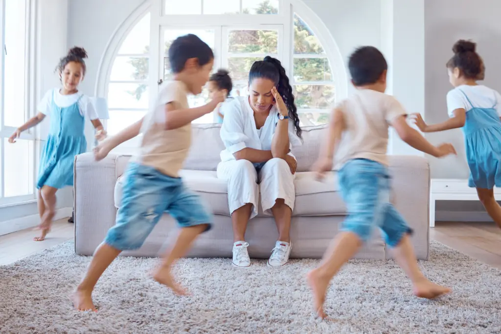 Mum with head in hands exasperated by kids running wild