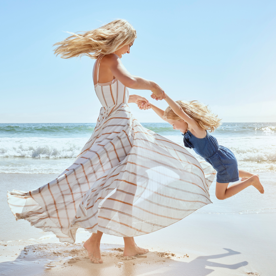 Mother twirling child on beach